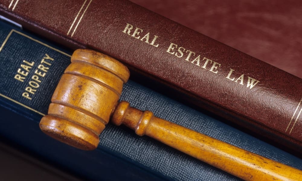 A gavel sits on top of a book of real estate law.